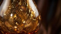 Golden amber whiskey swirling in glass with bubbles and light reflections creating luxury drinking experience for premium alcohol advertising.