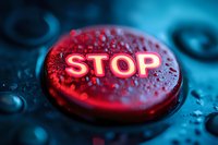 Red illuminated stop button with water droplets on dark background, dramatic macro photography showing texture and reflective surface in emergency lighting.