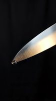 Sharp kitchen knife blade with dramatic lighting on black background for culinary and cooking concepts.