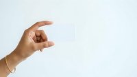 Hand holding blank white card or paper against neutral background, suitable for business presentations, marketing materials, and promotional designs.