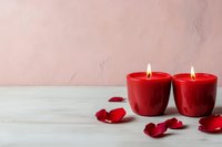 Two red burning candles with scattered rose petals on white wood, pink wall background, romantic Valentine's Day or anniversary celebration concept.