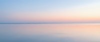 Serene pastel sunset over calm water with soft pink and blue hues creating peaceful minimalist seascape for meditation and wellness content.