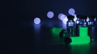 Laboratory vials with glowing green liquid in dark scientific research environment with bokeh lights for pharmaceutical and biotechnology studies.