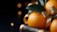 Fresh ripe oranges with golden ribbon bow and glitter sparkles on dark background with bokeh lights, festive winter holiday food styling composition.