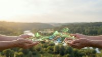 Hands protecting glowing green energy symbols over natural landscape representing environmental conservation, sustainability and eco-friendly technology solutions.