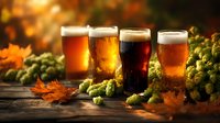 Variety of craft beer glasses with different brews surrounded by fresh hops and autumn leaves on rustic wooden table in warm golden light.