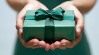 Hands holding elegant green gift box with satin ribbon bow for holidays, birthdays, celebrations and special occasions gifting moments.