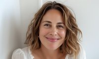 Confident middle-aged woman with wavy bob hairstyle smiling warmly against white background, wearing casual white sweater. Perfect for wellness, positivity, or natural beauty concepts.