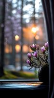 Delicate pink magnolia flowers in dark vase on windowsill at sunset, with soft bokeh lights and forest background creating cozy atmospheric mood for home decor.
