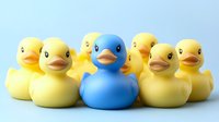 Rubber ducks group with one blue duck standing out among yellow ducks on light background, suitable for toy and product photography.