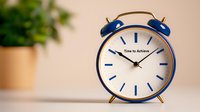 Blue retro alarm clock showing time to achieve text on white dial face, with blurred plant pot background creating motivational business concept.