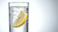 Refreshing sparkling water with fresh lemon slice and ice cubes in clear glass, perfect for beverage, wellness, and lifestyle design projects.