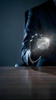 Businessman in dark suit holding glowing leadership badge with light effects, representing business success, management, and professional achievement for corporate concepts.