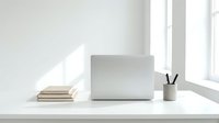 Clean minimalist workspace with laptop, books and pen holder on white desk near bright window for productivity and focus.