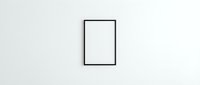 Empty black picture frame hanging on white wall for artwork display and interior design mockup presentations.