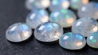 Collection of polished opal gemstones displaying iridescent rainbow colors and natural fire patterns on dark surface for jewelry making and design.