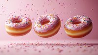 Floating pink glazed donuts with colorful sprinkles scattered in motion against soft pink background. Sweet dessert composition for bakery and confectionery design.