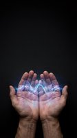 Male hands cupped together holding glowing blue energy waves on dark background representing power, healing, magic, and spiritual connection.