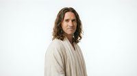 Middle-aged Caucasian woman with wavy brown hair wearing beige cardigan sweater on white background. Professional portrait for lifestyle content.