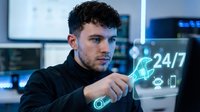 Young Caucasian male IT specialist working with holographic interface displaying 24/7 support icons in modern control room with multiple monitors.