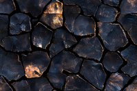 Cracked dark soil texture with copper highlights and deep fissures creates dramatic natural pattern. Abstract background for environmental themes.