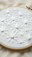 White daisy flowers hand embroidered on linen fabric in wooden hoop showcasing traditional needlework and textile art craftsmanship for DIY projects.