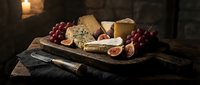 Assorted cheeses with red grapes, figs, and nuts arranged on wooden board with knife for gourmet food styling and culinary content.