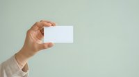 Hand holding blank white business card against neutral background, ready for custom branding and design mockups for corporate identity projects.