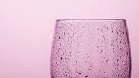 Pink textured glass with water droplets on matching background for beverage photography and kitchen design projects.