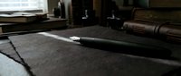 Elegant black fountain pen resting on dark textured paper, surrounded by vintage ink bottles and leather journal in moody studio setting.