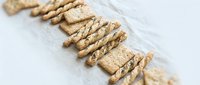 Crunchy whole grain crackers arranged in diagonal rows on white marble surface, showcasing texture and nutritional snack options for food styling and culinary content.