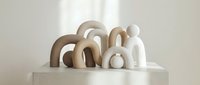 Minimalist ceramic sculptures with organic curved forms in neutral beige and white tones arranged on clean surface for modern interior design decor.