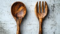 Rustic wooden spoon and fork on concrete background, handcrafted kitchen utensils with natural wood grain texture and artisanal design for food photography.