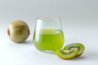 Fresh kiwi fruit juice in glass with whole kiwi and sliced fruit on white background, suitable for beverage, health and nutrition marketing.