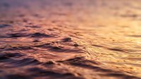 Ocean waves at golden hour with warm sunset colors reflecting on water surface creating peaceful seascape atmosphere for relaxation and meditation backgrounds.