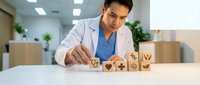 Healthcare professional arranging wooden blocks with medical icons in modern clinic office environment for patient care planning and organization.