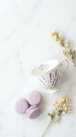 Elegant lavender teacup with purple macarons and dried flowers on white marble background for feminine lifestyle and tea time concepts.