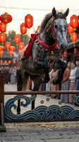 Gray horse in traditional red harness performing at Chinese New Year festival with red lanterns and crowd watching cultural celebration.