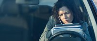 Stressed young woman driver looking frustrated while sitting in car during traffic jam or difficult driving situation.