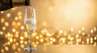 Champagne being poured into elegant glass with golden bokeh lights background for celebration, New Year, wedding, anniversary party atmosphere.