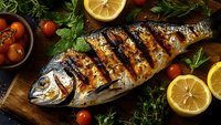 Grilled whole fish with lemon slices and fresh herbs on wooden board, perfect for restaurant menus and healthy cooking content.