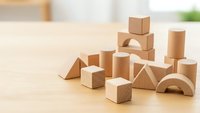 Natural wooden building blocks scattered on light wood surface for educational play and child development activities.