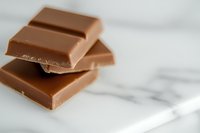 Stacked milk chocolate bars on white marble surface, ideal for food, confectionery, and culinary design projects.