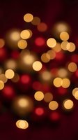 Warm golden and red bokeh lights creating festive atmosphere on dark burgundy background for holiday celebrations and seasonal decorations.