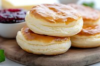 Fluffy Japanese souffle pancakes stacked on wooden board with berry jam, close up view showing airy texture and golden brown surface, food photography.