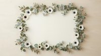 Elegant floral frame with white anemone flowers and eucalyptus branches on a light wooden background, copy space for text or design.