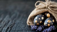 Decorated Easter eggs with golden dots in burlap sack with lavender flowers on dark wooden background for spring holiday celebration and festive decoration.