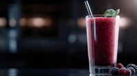 Refreshing berry cocktail with ice and mint garnish in a tall glass against blurred evening background, suitable for beverage, hospitality, and restaurant marketing materials.