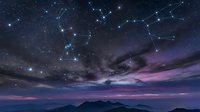 Night sky with constellation patterns connected by glowing lines over mountain silhouette at twilight. Starry astronomy background for astrology and celestial themes.