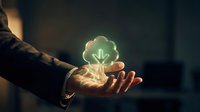 Professional businessman holding glowing green tree icon representing environmental sustainability and eco-friendly business growth concepts.